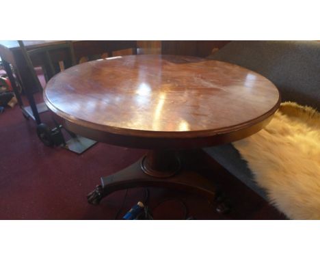 A mahogany circular tilt top table on tripod base with claw caster feet