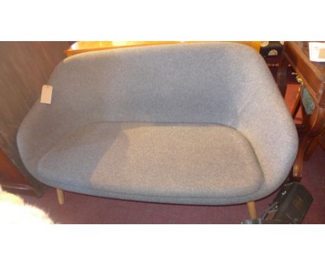 A Modernist style two seater sofa upholstered in grey fabric, raised on light oak supports 