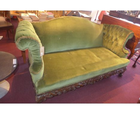 An Antique three seater sofa, upholstered in green velour, having buttoned scrolling arms, raised on ornately carved base, ca