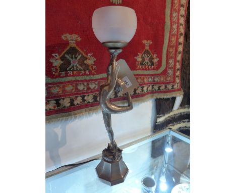 An Art Deco style silvered table lamp in the form of a lady holding a frosted glass shade aloft 