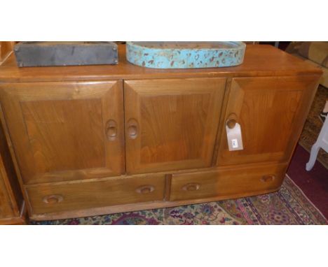 An Ercol elm sideboard, with three cupboard doors over two short drawers 