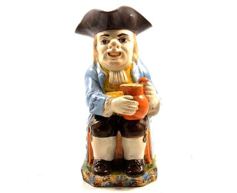 Late 18th/ early 19th century Pearlware Toby jug, seated with a jug of ale, pale blue overcoat, sponged decoration to the bas