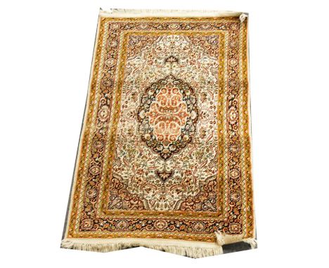 Persian silk rug, large burnt orange and black central medallion against a snad-coloured ground filled with scrolling leaves,