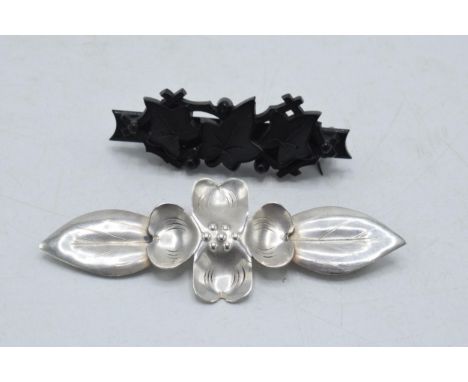A pair of vintage brooches to include white metal stylised floral brooch and a vulcanite ivy brooch (2).  