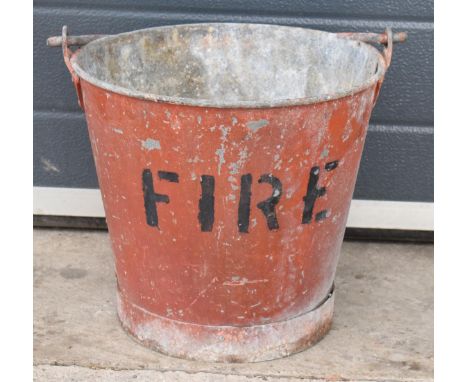 Vintage metal riveted fire bucket with swing-over handle painted red with 'FIRE' in black, 31cm tall with handle down.  