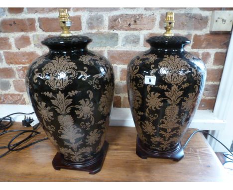 A pair of urn shaped ceramic table lamps, dark brown glaze with light brown foliate decoration on hardwood bases