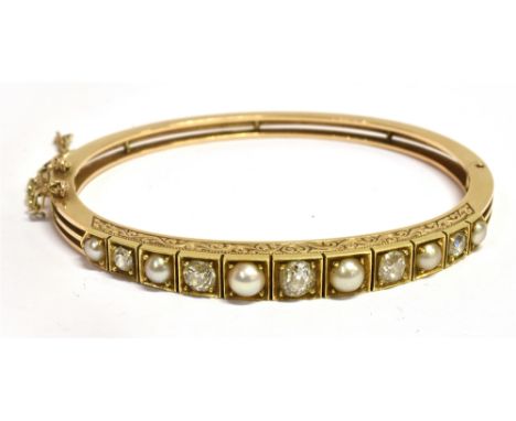 AN EDWARDIAN DIAMOND AND PEARL SET GOLD BANGLE  the graduating front section comprising five round old cut diamonds alternati