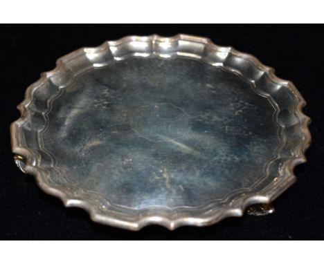 A SMALL SILVER SALVER  On three scroll feet, of hammered finish with plain central cartouche and scroll border 16cms diameter