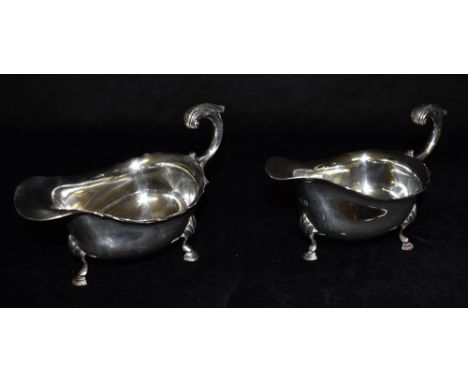 A PAIR OF SILVER SAUCE BOATS of traditional three footed design with scroll handles, hallmarked London 1911, makers D &amp; J