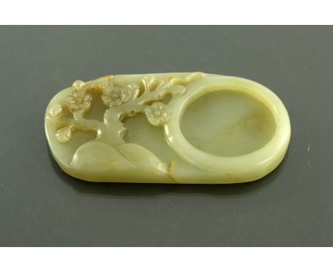 A Chinese carved jade scholar's palette dish, modelled in relief with a prunus tree, 11cm long