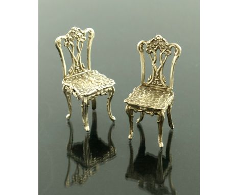 A pair of Elizabeth II miniature silver chairs, Richards and Knight, Chippendale form, embossed in the Dutch style, 5.5cm hig