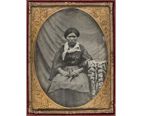 *Ambrotype. An ethnographic portrait of a woman seated at a table, c. 1860s,  quarter plate, oval aperture, embossed wooden l