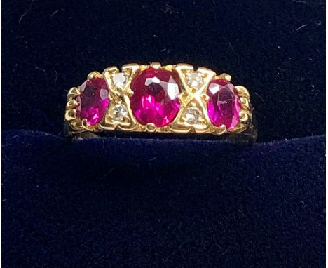 18ct gold diamond and ruby ring set with 3 rubies largest measures approx 5.5mm by 5mm with 4 small diamonds 