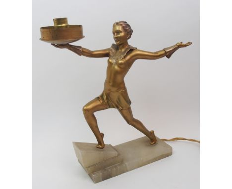 An Art Deco spelter table lamp modelled as a dancing woman with one leg raised on an onyx step, one arm stretched forward hol