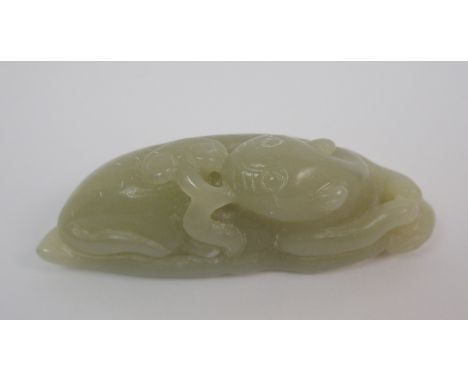 A Chinese hardstone carving of a feline recumbent with scroll in mouth and resting on a leaf, 7.5cm wide
