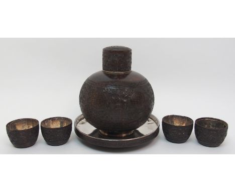 A Chinese coconut and silver mounted set comprising; bottle decanter and stopper, 15cm high, stand, 15.5cm diameter and four 