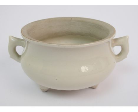 A Chinese white glazed tripod censer with lug handles, with unglazed inner rim, perhaps Ming Dynasty, 13cm wide, bears label 