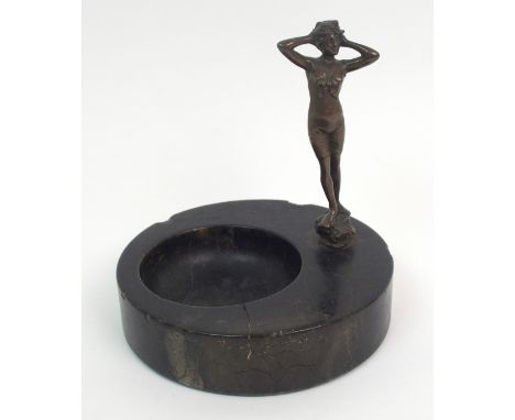 An Art Deco veined black marble trinket dish with bronzed figure of a lady in swimming costume, standing on a rocky outcrop, 