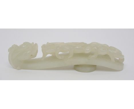A Chinese jade button hook carved with a chilong confronting a grotesque head, 11cm long