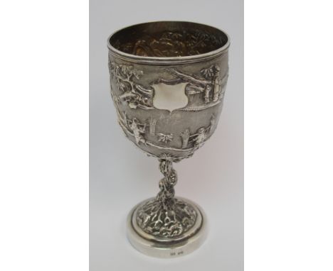 A Chinese Export silver goblet decorated with various figures in a mountainous landscape amongst pine, bamboo and blossoming 