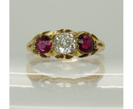A bright yellow metal ruby and diamond ring in a scalloped setting, the central cushion cut diamond is estimated approx 0.50c