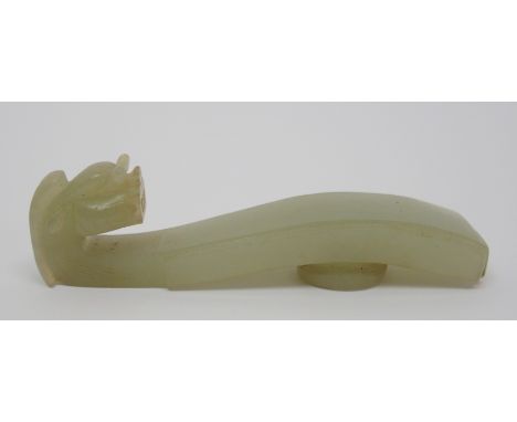 A Chinese jade button hook carved with a grotesque animal head with hair running down and open pierced mouth, 8cm long