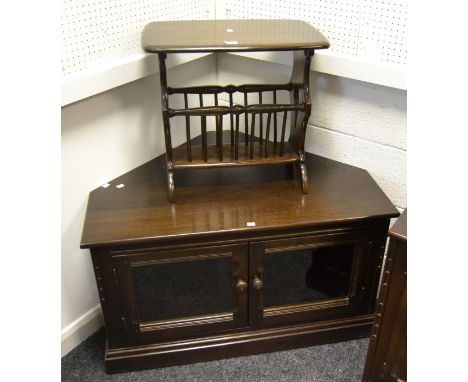 A dark oak Ercol corner TV stand, two glazed doors, plinth base; a conforming Ercol magazine rack/ side table