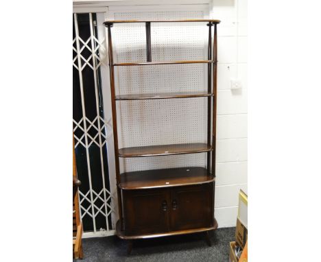 An Ercol room divider, two rounded shelves, two adjustable shelves above projecting base enclosing cross panelled doors