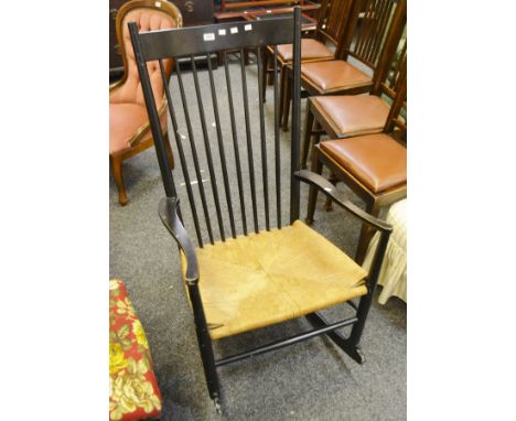 A mid 20th century rush seated , stick back rocking chair , painted black