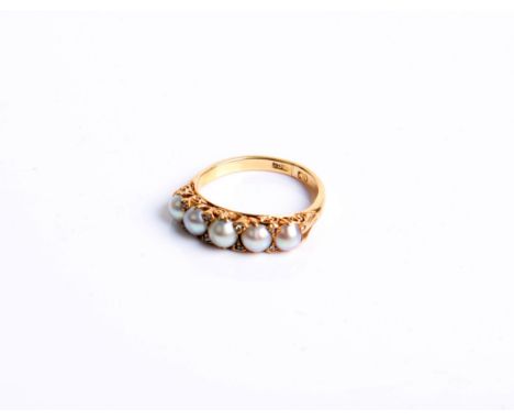 An Edwardian gold and half pearl five stone carved half-hoop ring with rose diamond points, with a scroll carved gallery on a