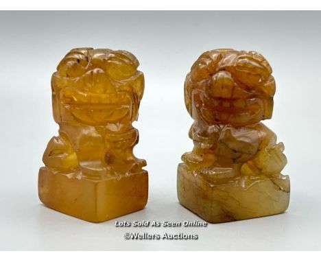 A pair of small carved orange jade foo dogs, each 4.5cm high / AN47