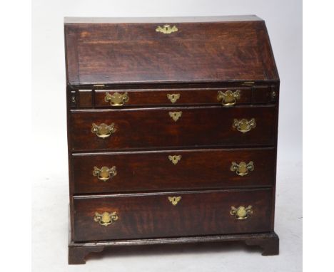 An early 19th century oak bureau, the hinged fall front enclosing a compartmentalised interior with drawers, and a sliding co