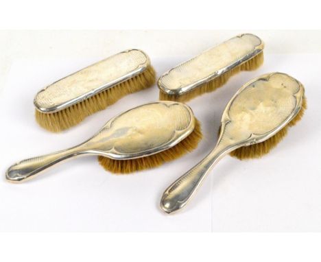 A George V hallmarked silver backed four piece dressing table set comprising two hand brushes with overall engine turned deco