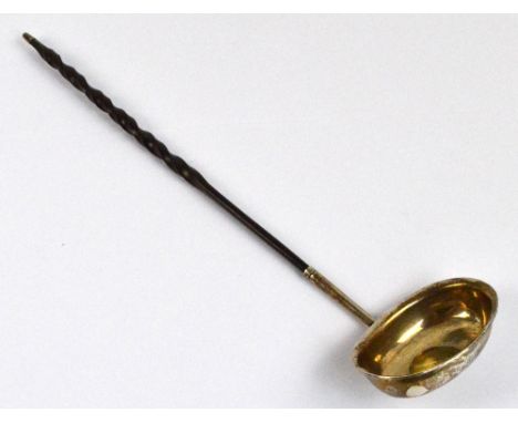 A George III white metal and wrythen baleen handled toddy ladle, the plain oval bowl with flared rim set with bank token 1S6D
