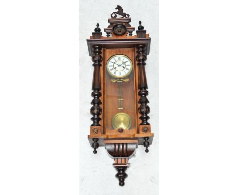 A late 19th century stained beech spring driven Vienna style wall clock with white enamel dial set with Roman numerals and el