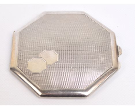 A George VI hallmarked silver octagonal powder compact with overall engine turned decoration, with double vacant cartouche to