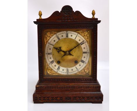 An early 20th century German oak eight day mantel clock with shaped pediment above square dial set with silvered chapter ring