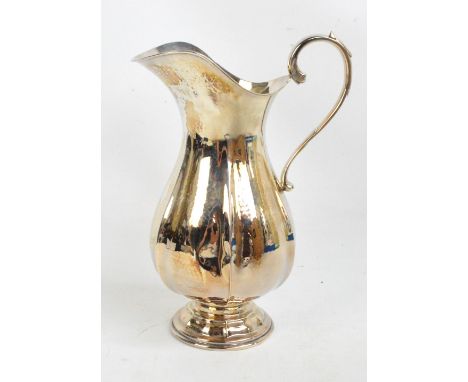 A large Elizabeth II hallmarked silver jug of panelled baluster form with broad rim and loop handle, raised on domed circular