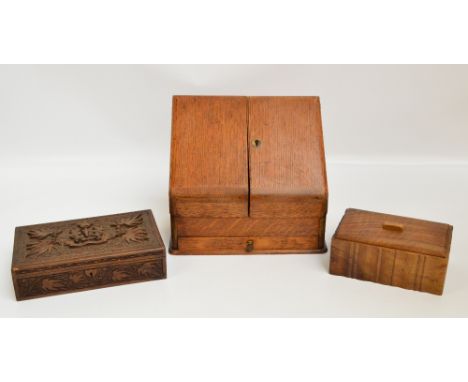 An Edwardian oak stationery box with sloping twin door front and compartmentalised interior above single pull-out drawer, wid