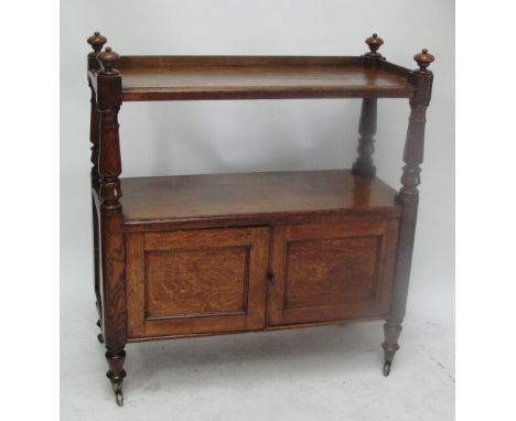 A Victorian oak buffet, the upper shelf with plain gallery and four squat finials, turned supports, lower shelf above a pair 