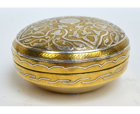 An early 20th century Cairo Ware brass circular box and cover, silver inlaid with ornamental and foliate scroll motifs to the