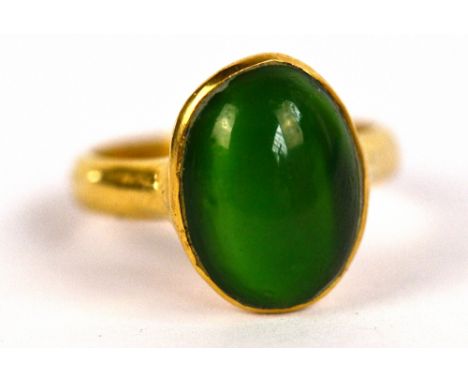 A yellow metal and oval green cabochon set ring, size K, approx 7.1g.