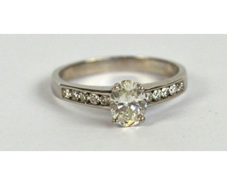 An 18ct white gold diamond ring, the principal oval cut stone weighing approx 0.7cts, with ten further small diamonds to the 