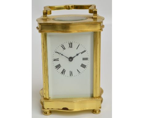 A 20th century brass cased carriage clock with serpentine shaped base and top, the rectangular enamel dial set with circular 