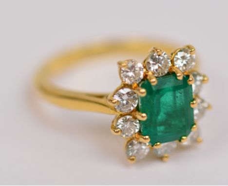 BOODLE & DUNTHORNE; an 18ct yellow gold emerald and diamond ring, the central emerald cut emerald within a border of ten diam