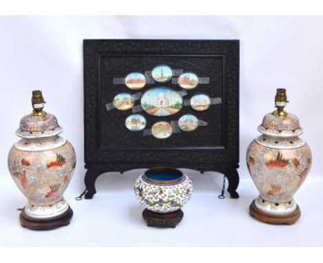 An Indian ebonised carved wood screen decorated with scrolling flowers and set with oval painted vignettes of landmark palace