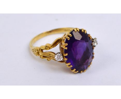 An 18ct yellow gold amethyst and diamond ring, the large oval amethyst flanked by raised diamonds in an elaborate pierced cla