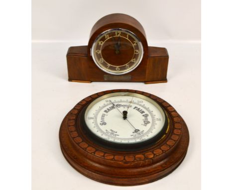 A 1920s carved oak wheel barometer, diameter 32cm, and a 1930s walnut electric mantel clock with applied pierced circular cha
