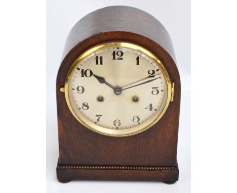 A 1930s oak domed eight day mantel clock, the circular silvered dial set with Arabic numerals, with pedestal bead decorated b