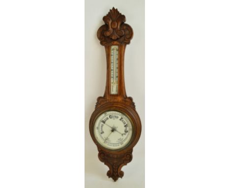 A late 19th century aneroid banjo barometer with carved oak case, circular white enamel dial, and thermometer above, height 9